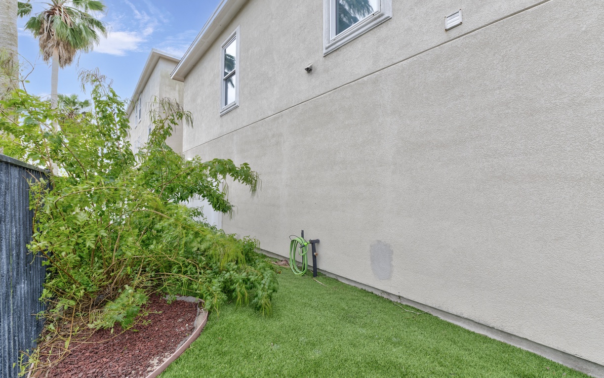Modern property exterior featuring manicured landscaping with tropical palm trees and well-maintained grounds.