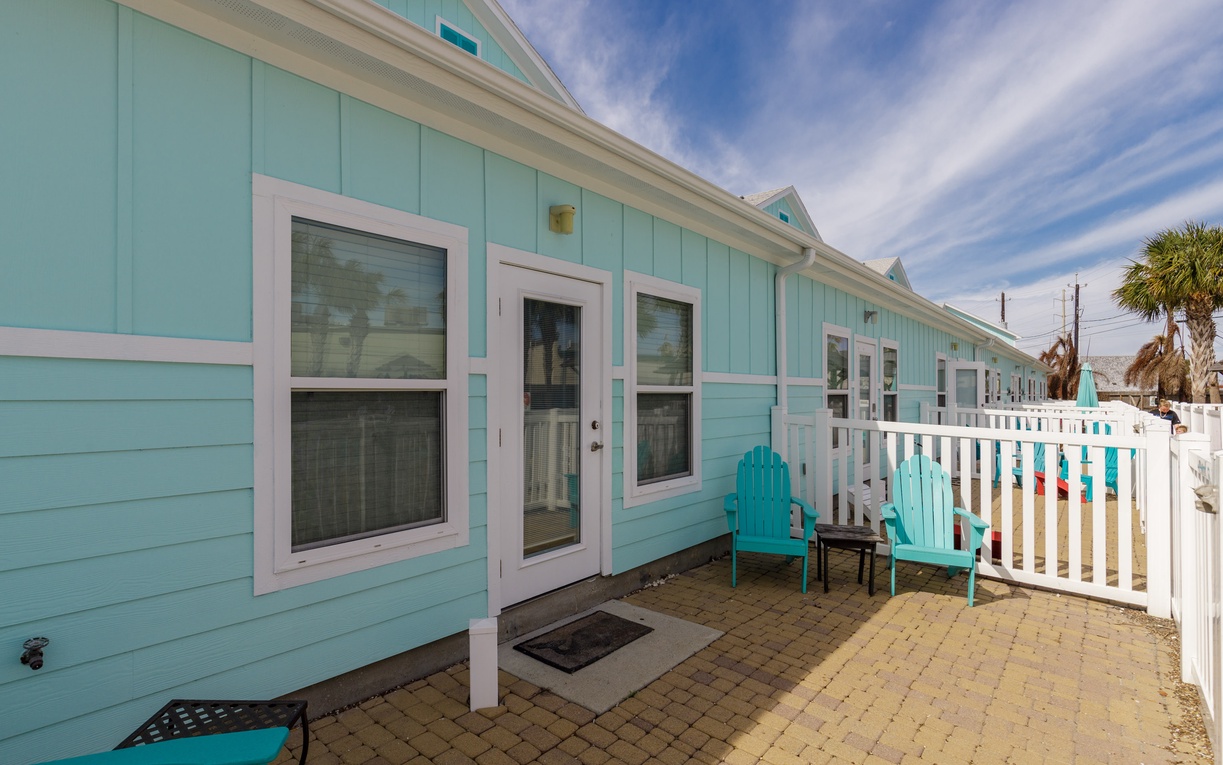 Charming turquoise cottage with cheerful patio seating and coastal charm for your perfect beach getaway.