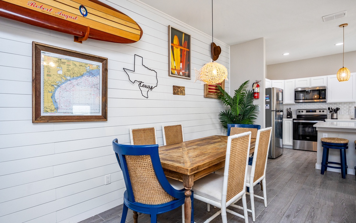 Gather around this coastal-inspired dining space where your meals become memorable moments beneath warm pendant lighting and charming nautical décor.