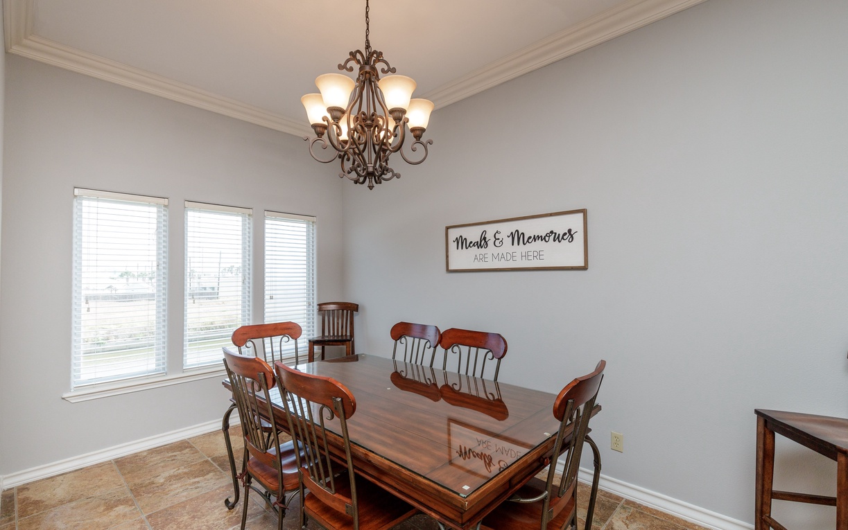 Gather around your elegant dining table where the warm chandelier creates perfect ambiance for memorable meals together.