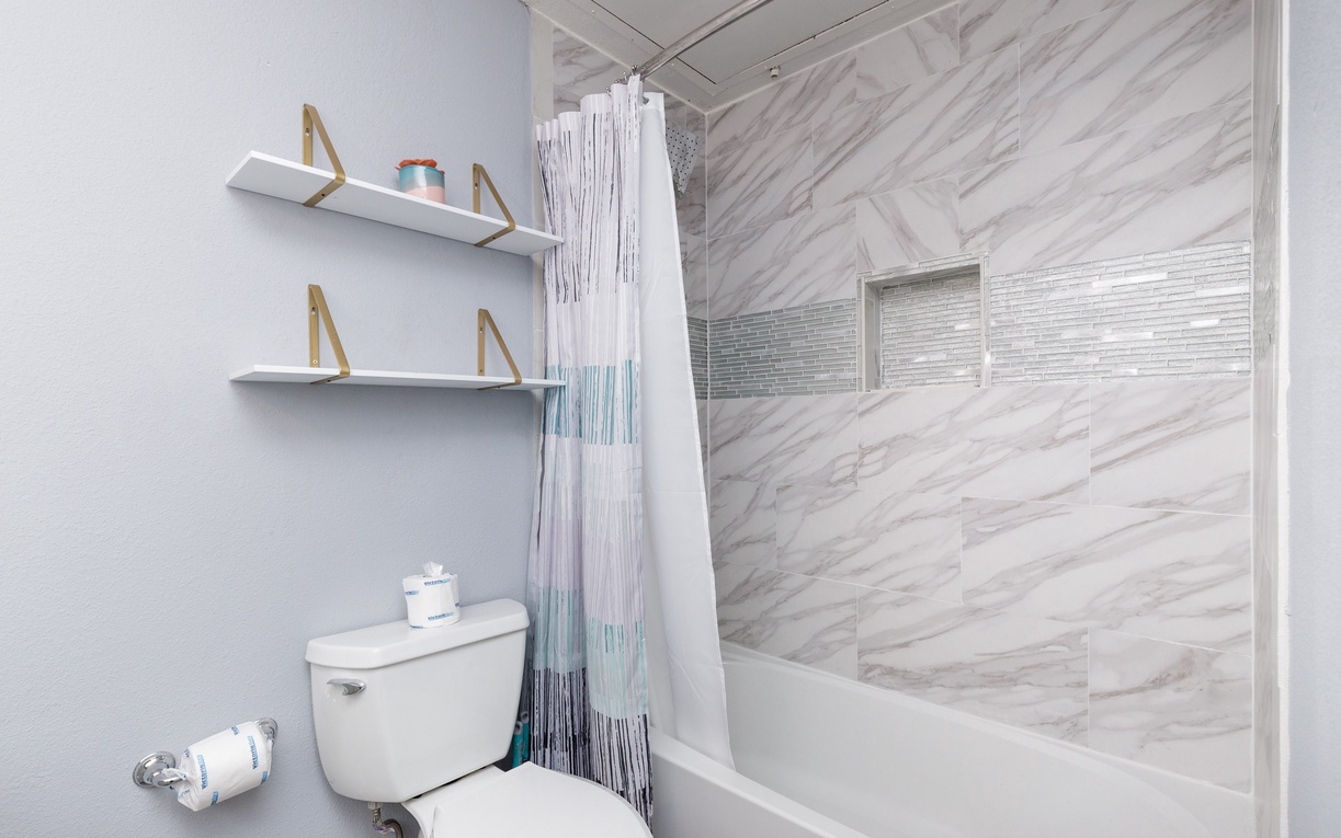 Step into your spa-like bathroom featuring luxurious marble-look tiles and modern gold-accented shelving for all your essentials.