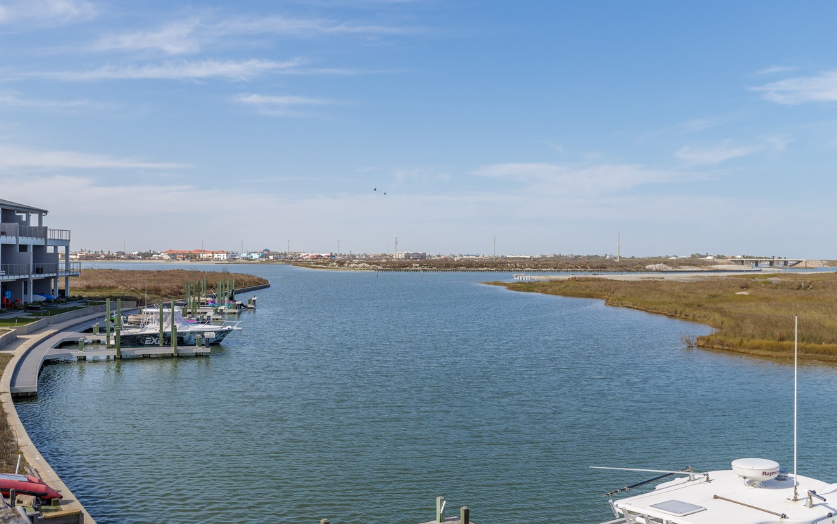 Waterfront property overlooking a peaceful marina with boats and natural marshland stretching to the horizon.