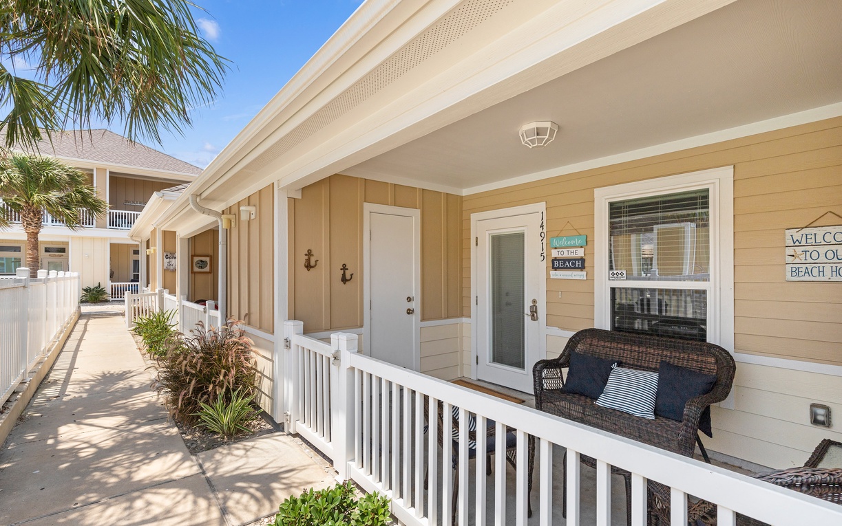 Charming beach cottage with covered porch seating and coastal decor welcomes guests to a tropical escape.