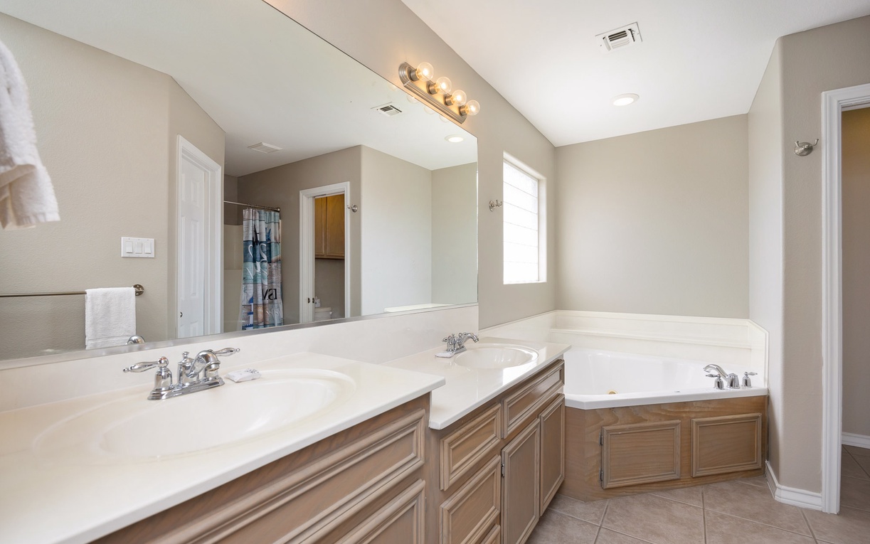 Unwind in your spacious master bathroom featuring dual sinks, a soaking tub, and elegant fixtures for ultimate relaxation.