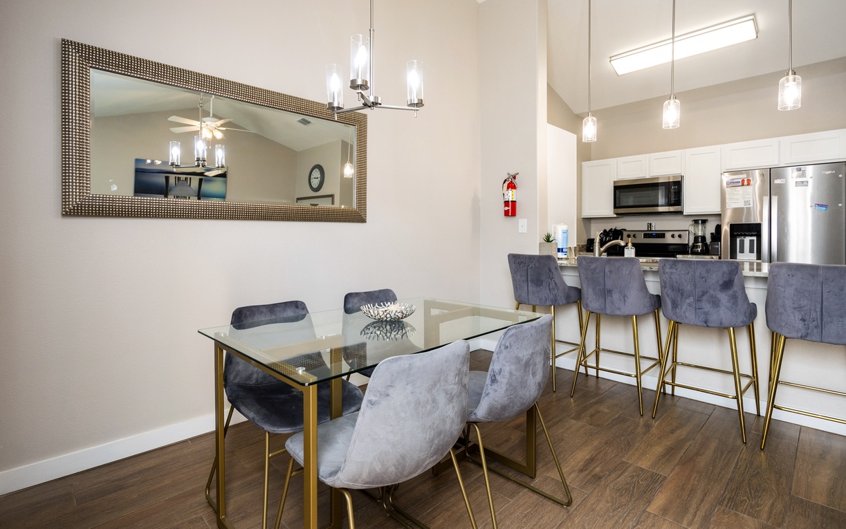 Gather around your elegant glass dining table with luxurious velvet chairs, where golden accents and modern lighting create the perfect atmosphere for memorable meals together.