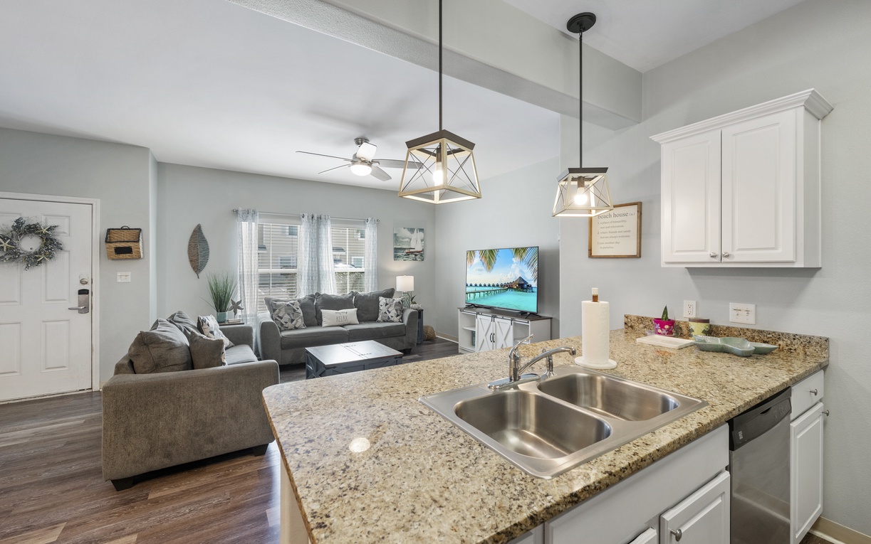 Your open-concept kitchen flows seamlessly into the living area, where granite countertops and modern pendant lighting create the perfect space for cooking while staying connected.