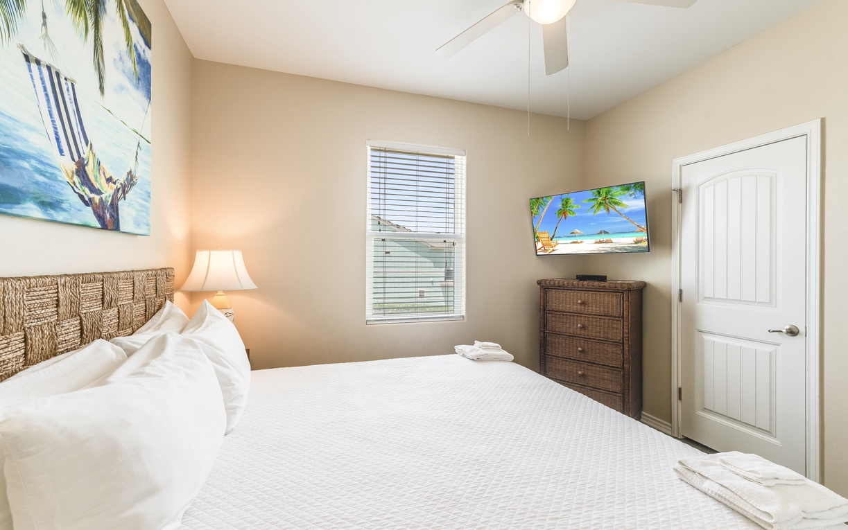 Drift off to sleep in your tropical-themed bedroom, where coastal artwork and warm lighting create the perfect beachside retreat ambiance.
