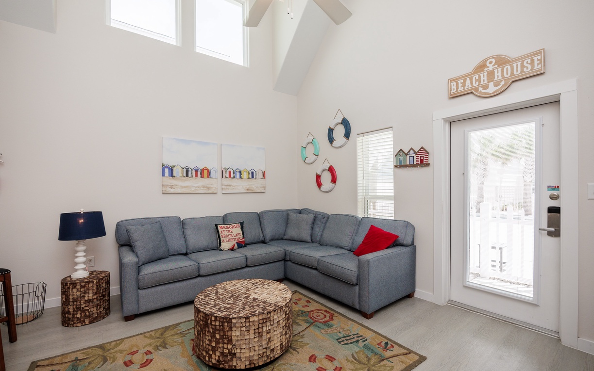 Relax in your bright living space with soaring ceilings, coastal charm, and a comfy sectional perfect for unwinding after beach adventures.