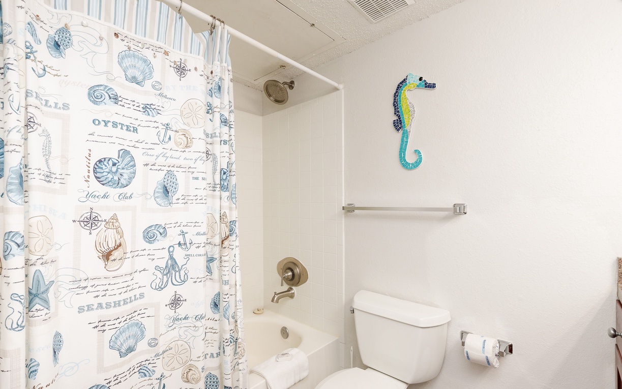 Your bright bathroom features a whimsical ocean-themed shower curtain and cheerful seahorse decor, creating a coastal vibe.