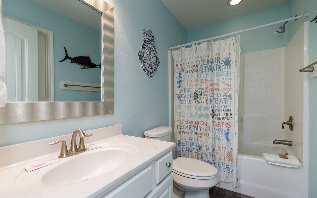 Refresh in your coastal-themed bathroom with ocean blue walls, nautical decor, and a relaxing tub-shower combo.