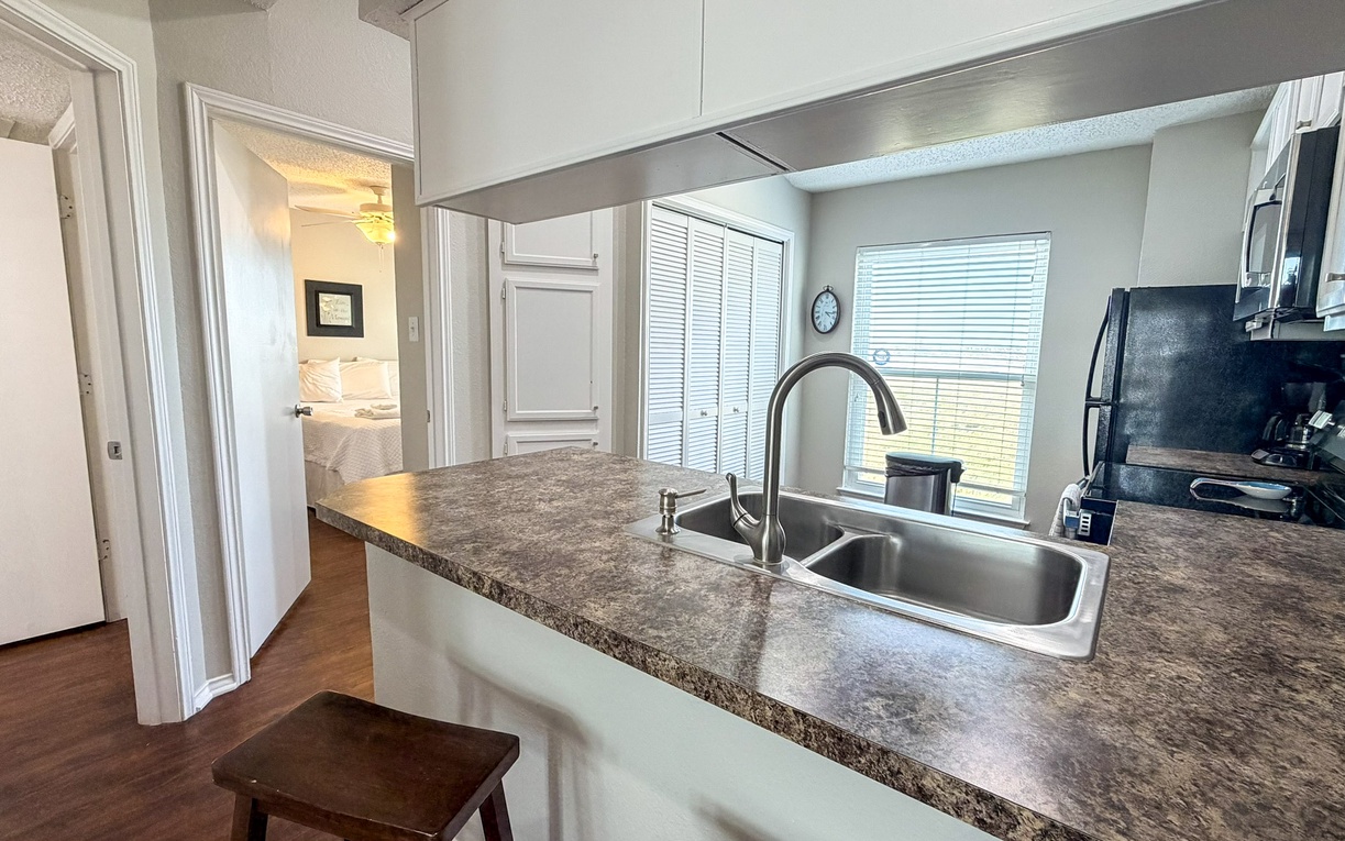 Your modern kitchen features granite countertops, stainless appliances, and natural light streaming through windows as you prepare meals.