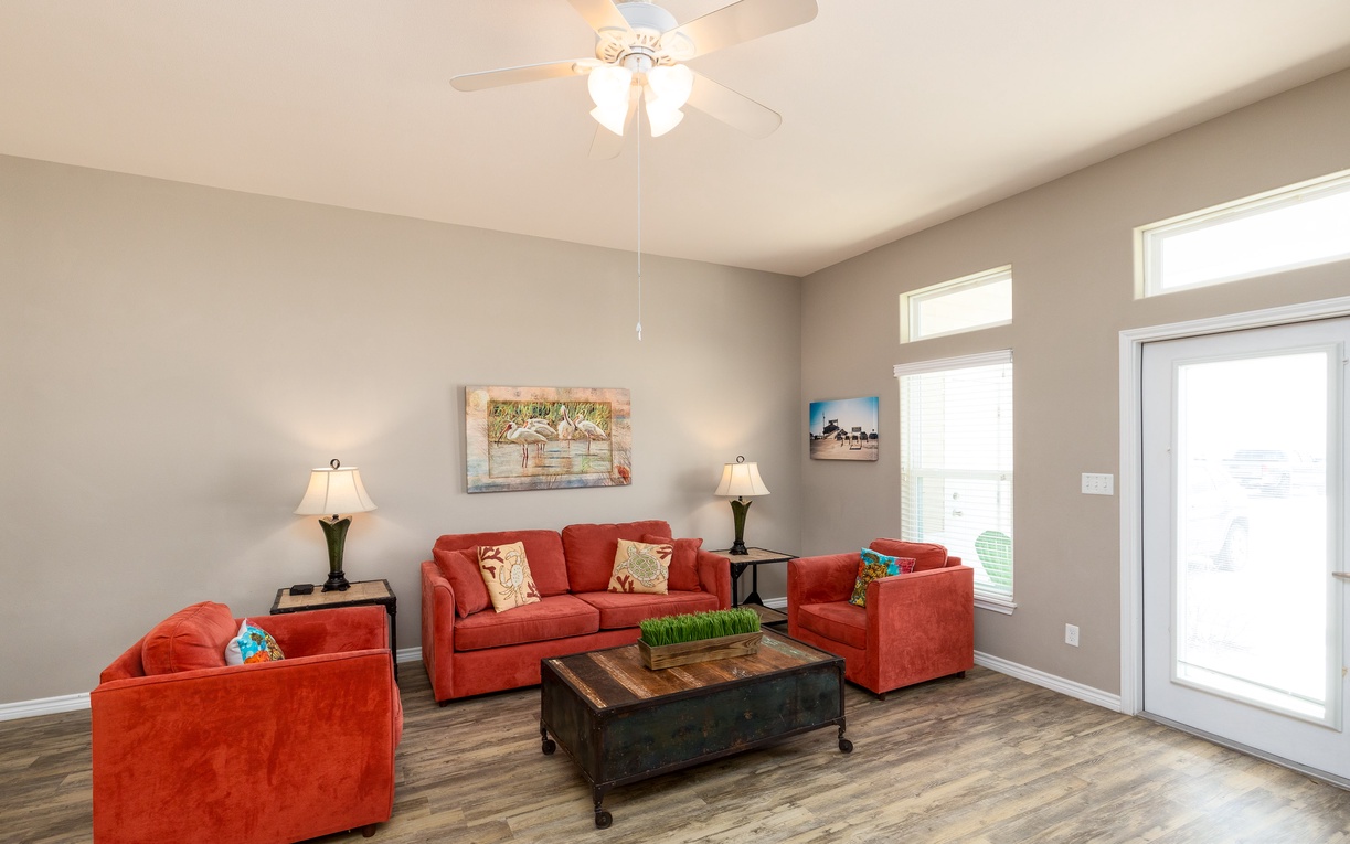 Unwind in this bright living room where vibrant orange sofas and warm lighting create your perfect retreat for evening conversations.