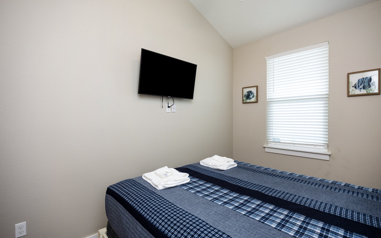 Relax in your peaceful bedroom with crisp linens, a wall-mounted TV for cozy evenings, and bright natural light.