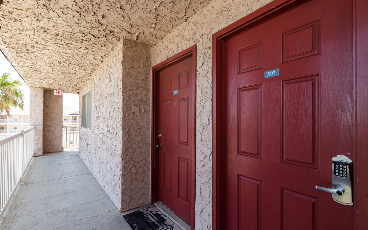 Property entrance hallway featuring adjacent units with distinctive red doors and keypad entry systems for secure access.