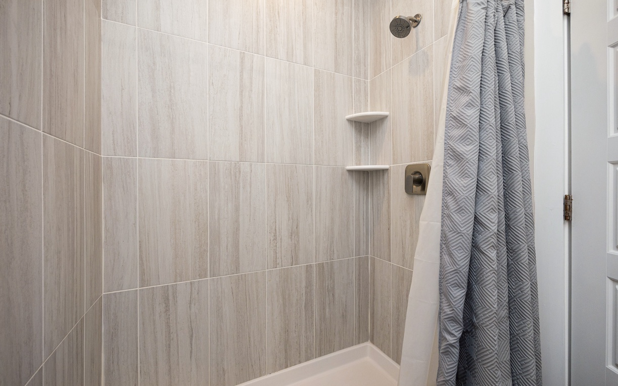 Step into your private shower oasis with elegant wood-grain tiles, built-in shelves for toiletries, and soft towels awaiting your refreshing escape.