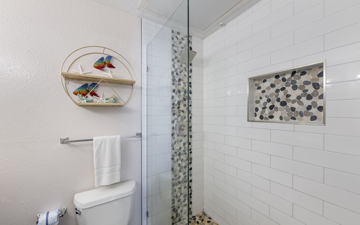 Your private bathroom features a stunning walk-in shower with beautiful pebble accents and a glass enclosure for a spa-like experience.