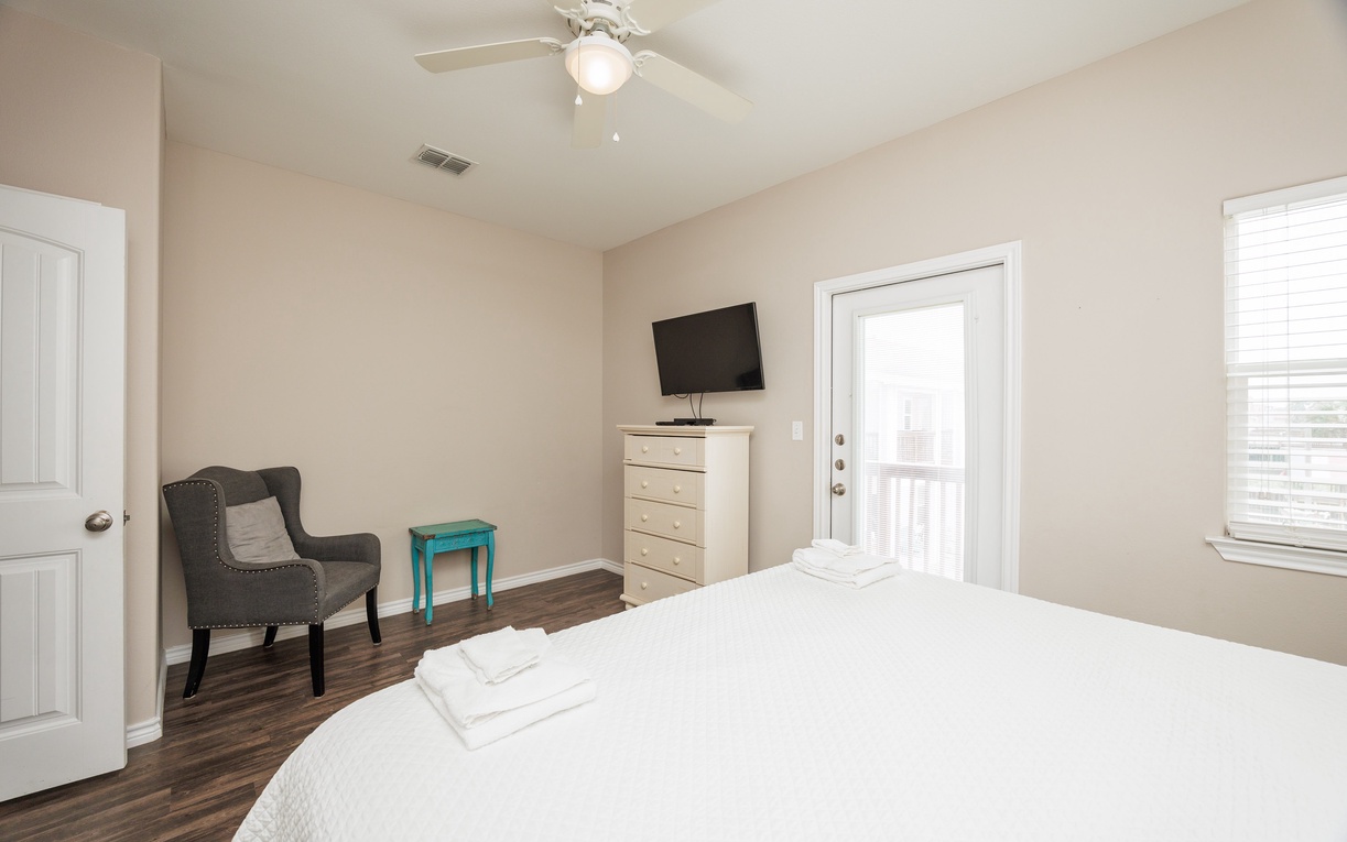 Unwind in your stylish bedroom featuring a plush bed, cozy reading chair, and private balcony access for peaceful mornings.