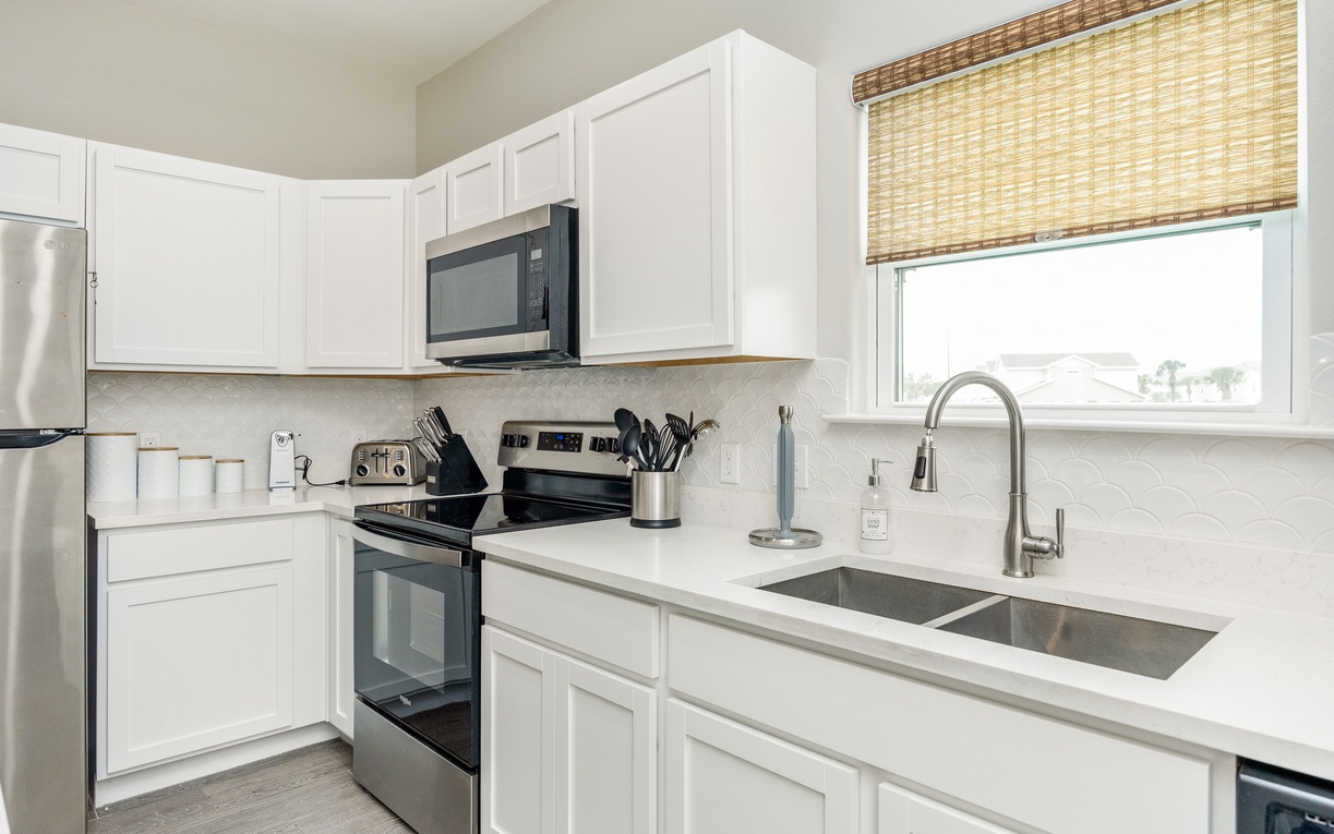 Your bright, fully-equipped kitchen features white cabinetry, stainless appliances, and a window view - perfect for preparing meals during your stay.