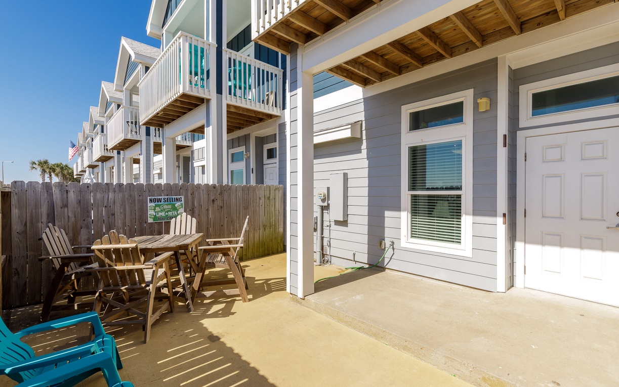 Step onto your private patio where wooden chairs await under the covered terrace, perfect for morning coffee or evening relaxation in this coastal retreat.