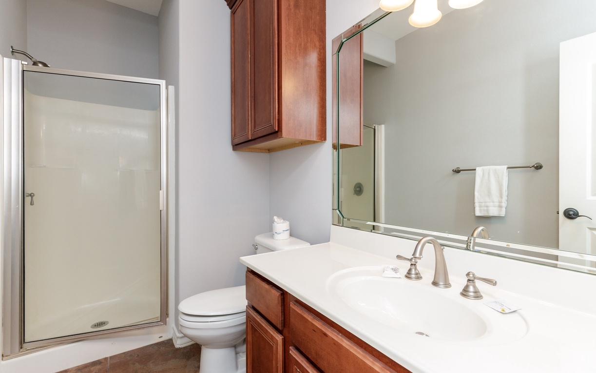 Your private bathroom features a spacious walk-in shower and elegant marble countertops with warm wood cabinetry for all your essentials.