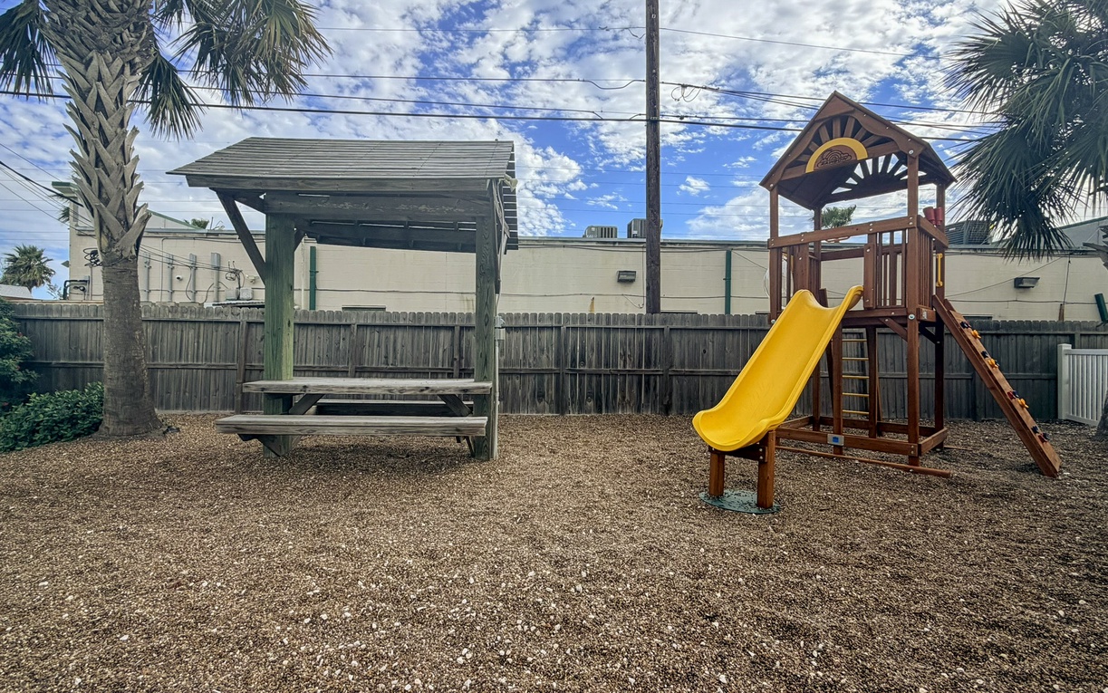 Your little ones will love the dedicated playground with its wooden climbing structure and bright yellow slide, while you relax at the covered picnic table nearby.