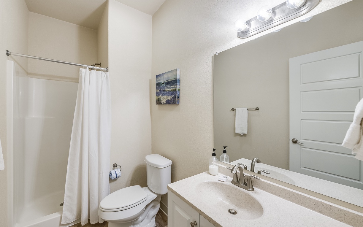 Fresh white towels await your arrival in this clean, well-lit bathroom with modern fixtures and thoughtful touches.