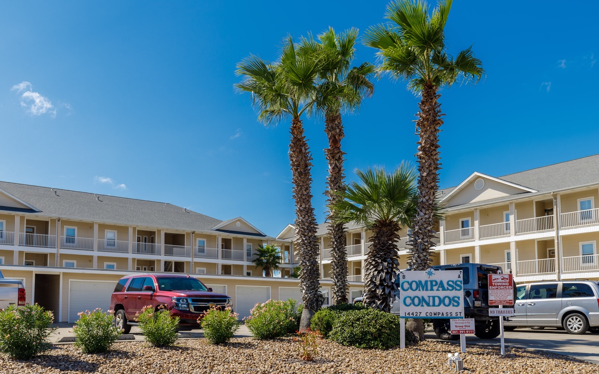 Compass Condos welcomes guests with palm-lined grounds under brilliant blue skies in this coastal vacation destination.