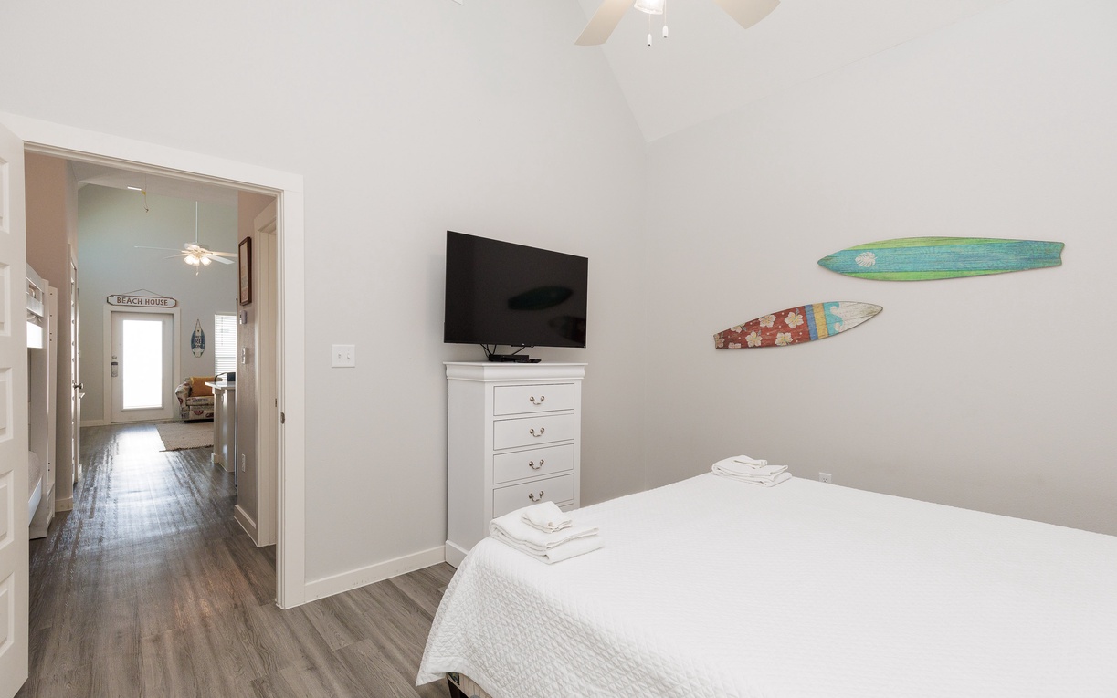 Relax in your coastal-themed bedroom with beach-inspired surfboard art, ceiling fan, and crisp linens for dreamy nights.