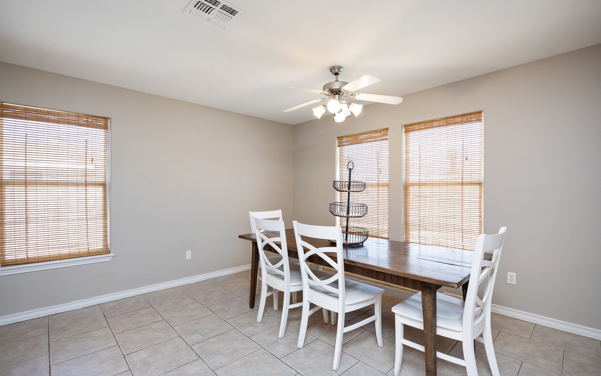 Gather around your private dining table where natural light streams through bamboo blinds, creating the perfect setting for memorable meals together.