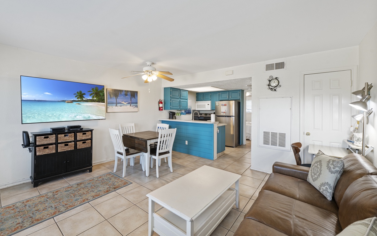 Relax in your open-concept retreat with turquoise kitchen, leather sofa, and large TV perfect for unwinding after beach days.