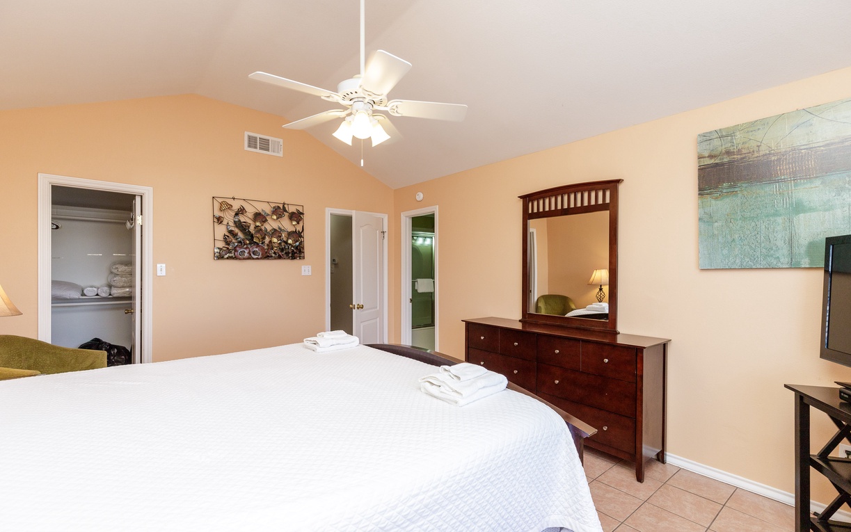 Your spacious bedroom features crisp linens, rich wood furnishings, and a gentle ceiling fan for perfect comfort during your stay.