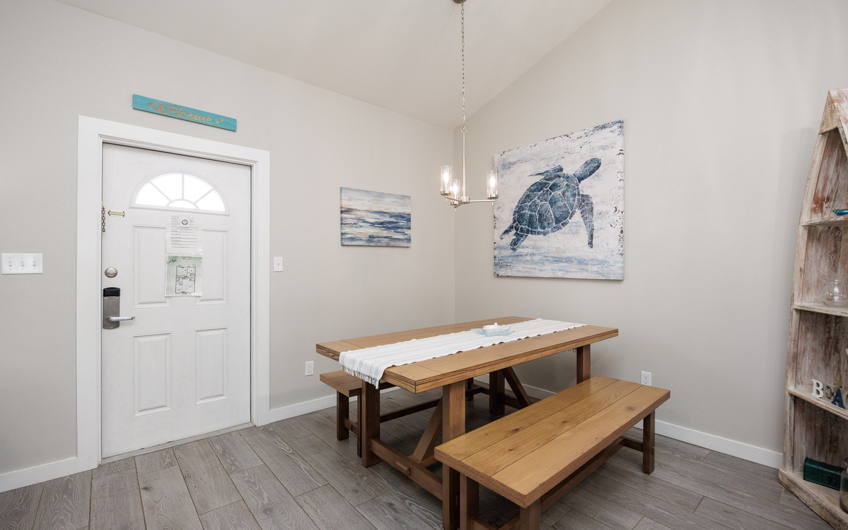 Your coastal dining space features a rustic wooden table with benches, perfect for sharing meals surrounded by charming sea turtle artwork.