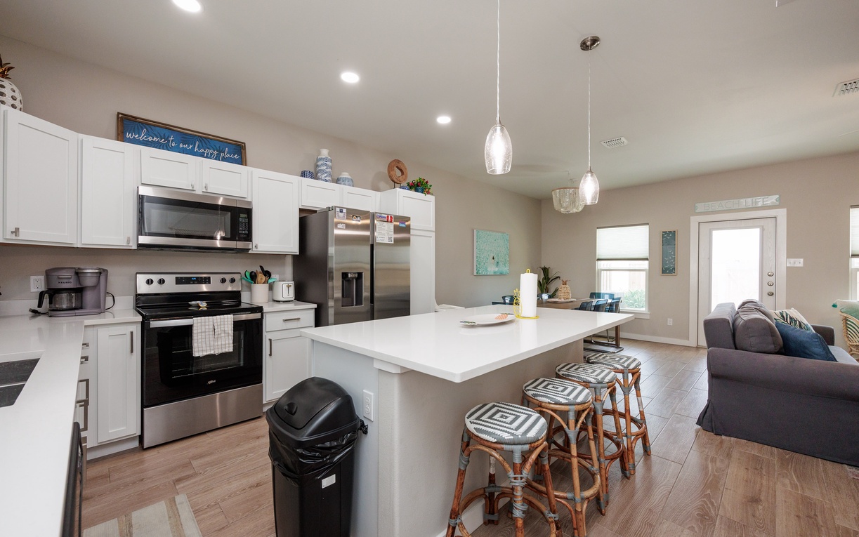 Your modern kitchen awaits with crisp white cabinets, stainless appliances, and a spacious island perfect for morning coffee or evening meals.