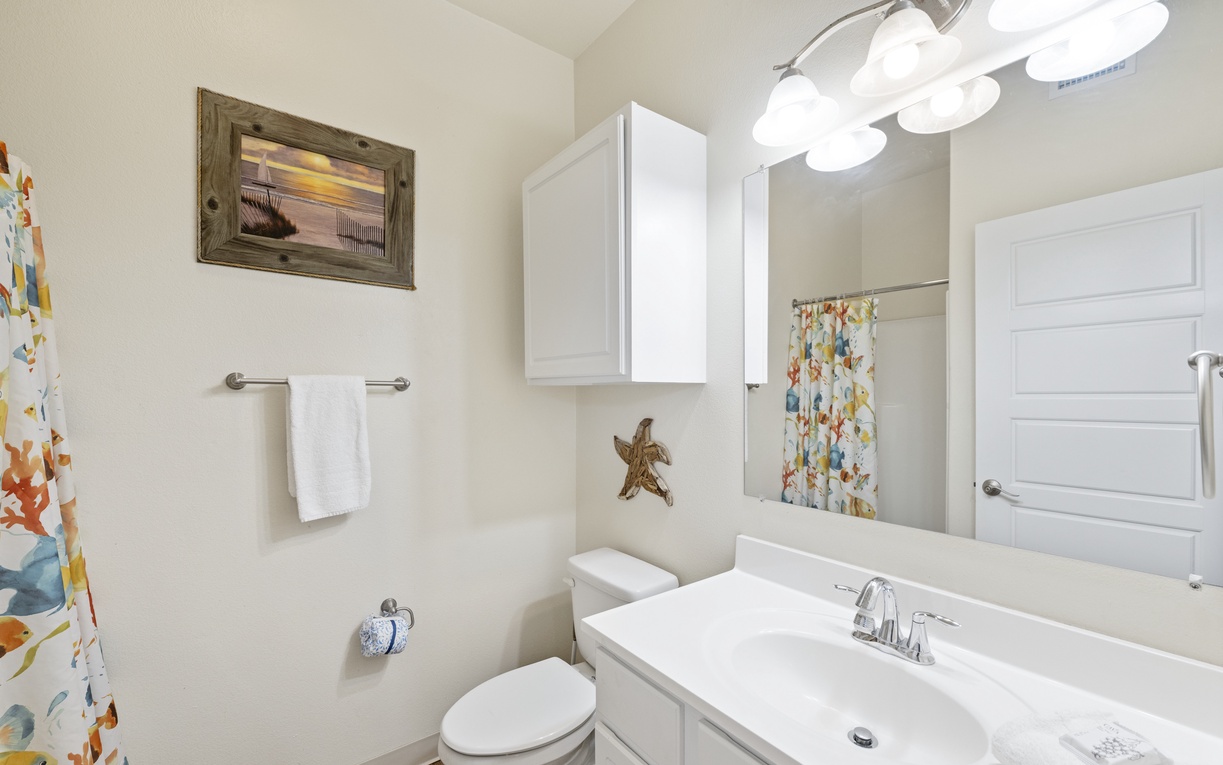 Freshen up in your bright, coastal-themed bathroom with crisp white fixtures and cheerful beachy décor that makes your morning routine feel like a seaside retreat.