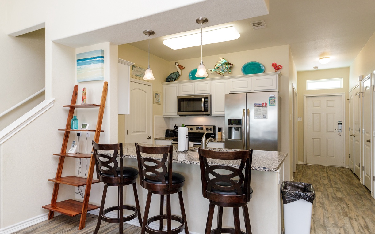 Gather around your bright kitchen island with swivel bar stools, perfect for morning coffee or evening cocktails with coastal-themed touches throughout.