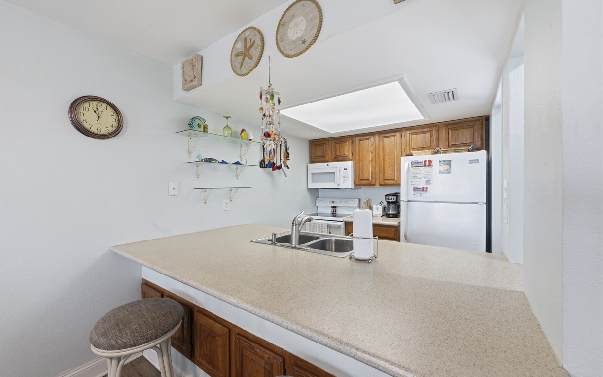 You'll love the fully-equipped kitchen with modern appliances, warm wood cabinetry, and coastal-themed decor, ready for preparing your favorite meals during your stay.