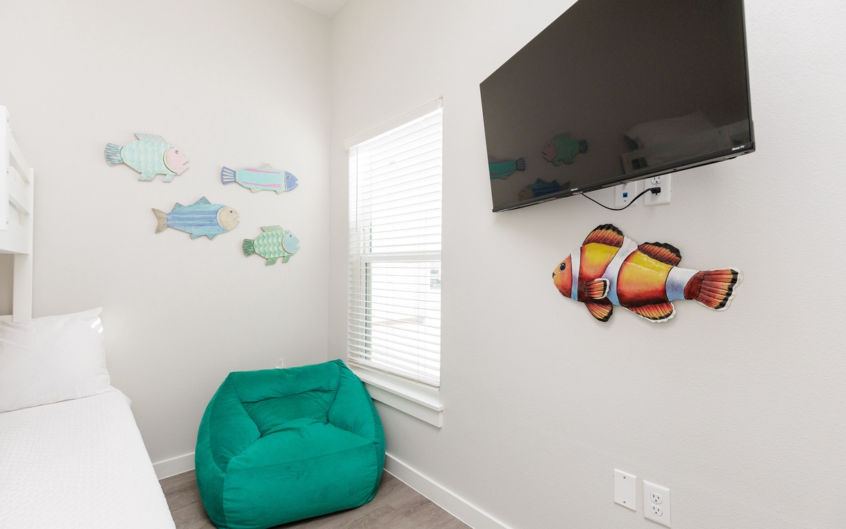 Relax in your cozy corner with whimsical fish art and a fun teal bean bag, perfect for unwinding after beach adventures.