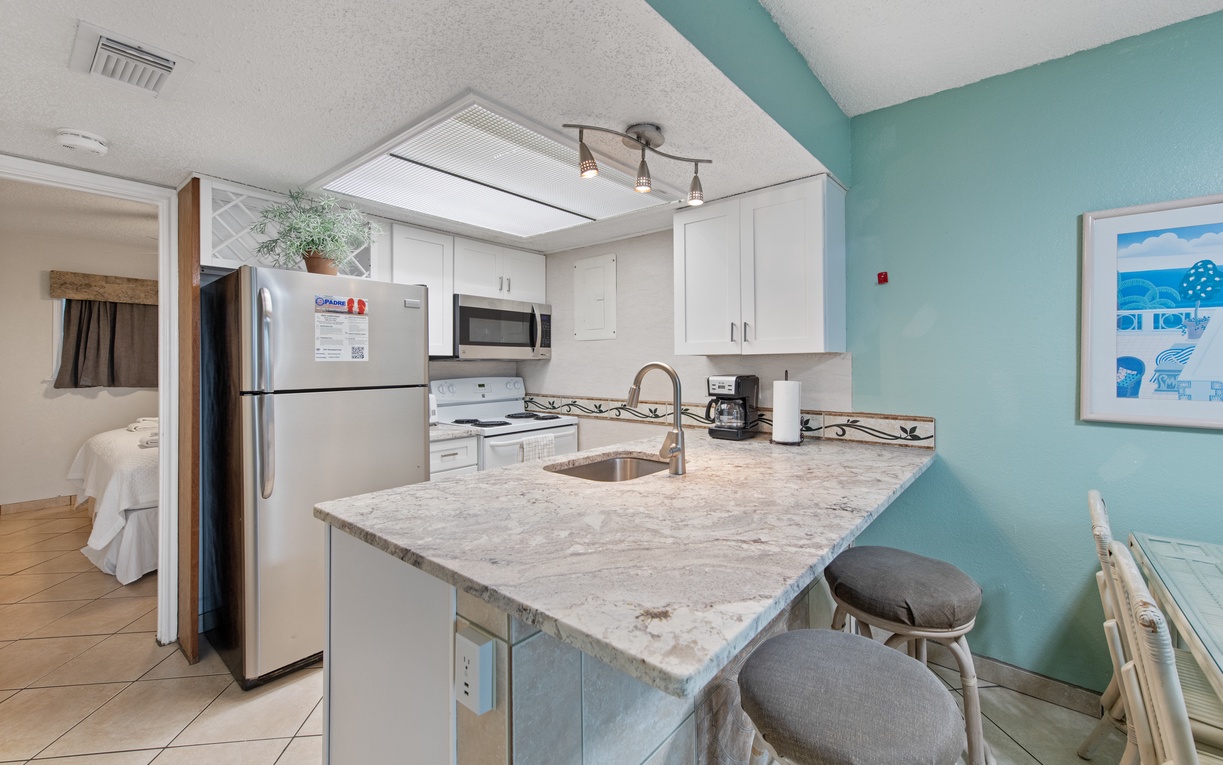 Your fully equipped kitchen features modern appliances, granite countertops, and a breakfast bar where you can enjoy coffee while planning your beach adventures.