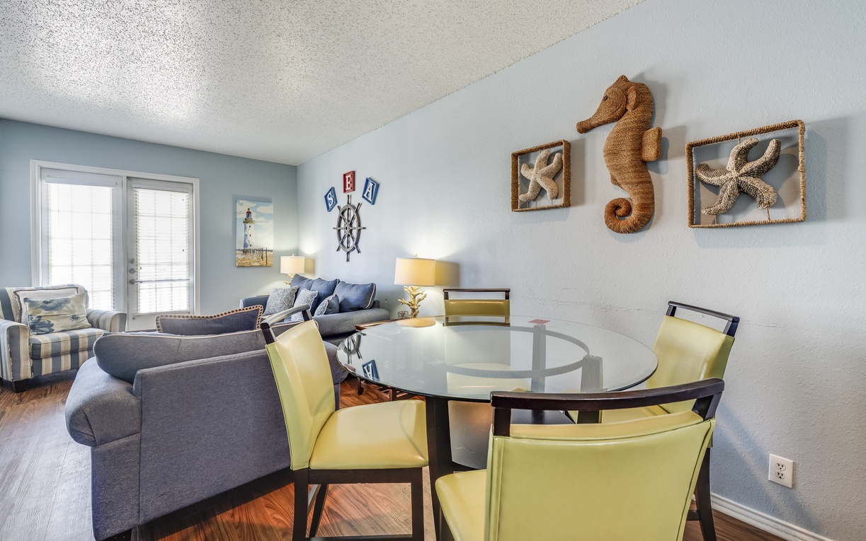 Unwind in your coastal-themed living space where nautical touches and cheerful yellow dining chairs create the perfect beach retreat atmosphere.
