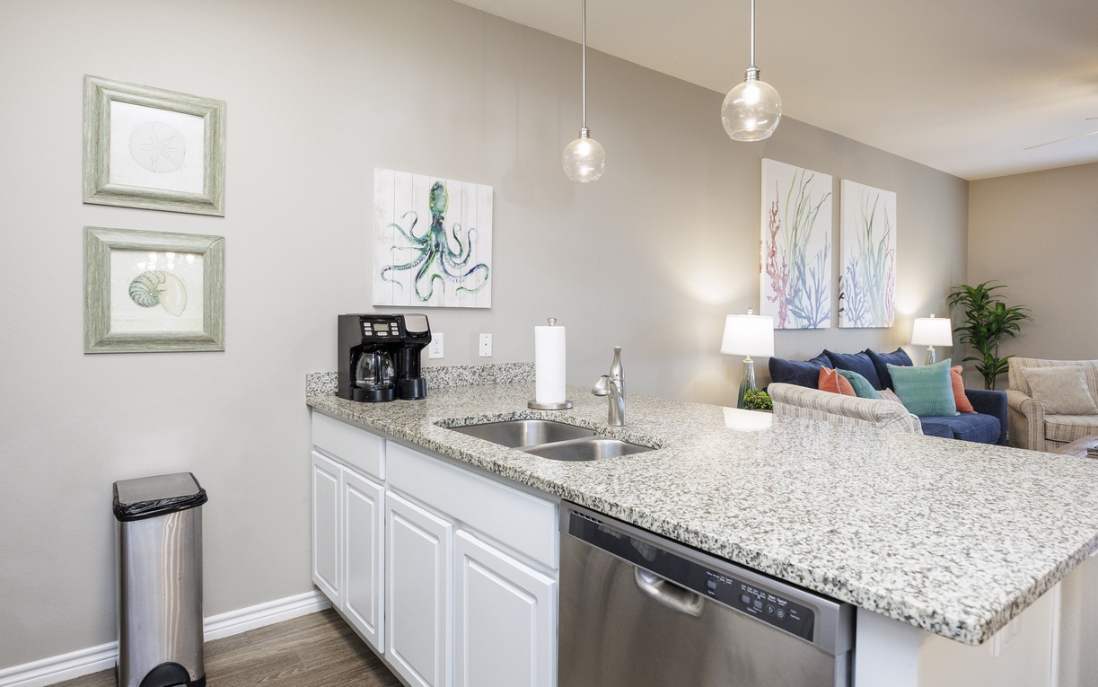 Your stylish kitchen features granite countertops, modern appliances, and ocean-inspired artwork that creates a bright, welcoming space.