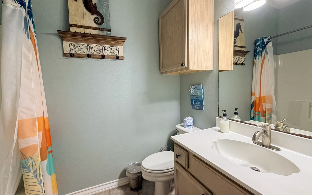 Step into your private bathroom featuring warm wood cabinetry, soothing coastal colors, and thoughtful touches that make freshening up a pleasure.