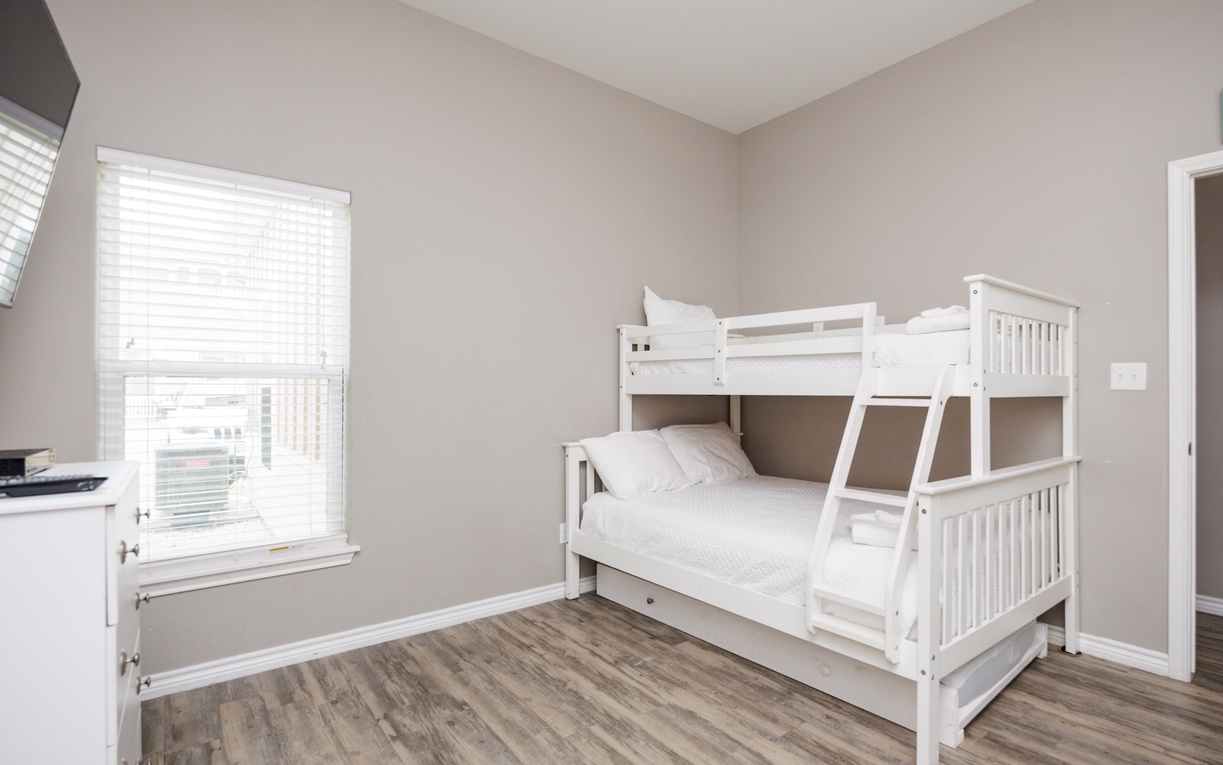 Your kids will love sharing this bright bedroom with sturdy white bunk beds and plenty of natural light streaming through the windows.