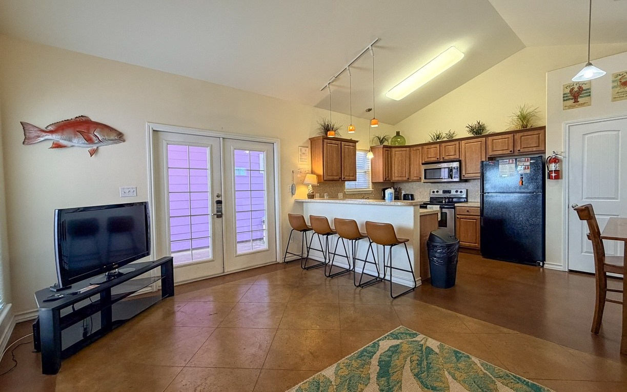 Relax in your open-concept living space where coastal charm meets modern comfort, featuring a full kitchen and entertainment area for memorable vacation moments.