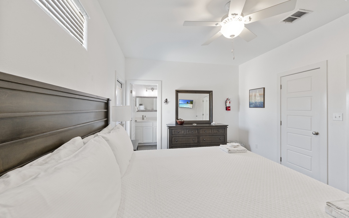 Drift into peaceful slumber in your bright, airy bedroom featuring a plush bed, elegant furnishings, and cooling ceiling fan for perfect comfort.