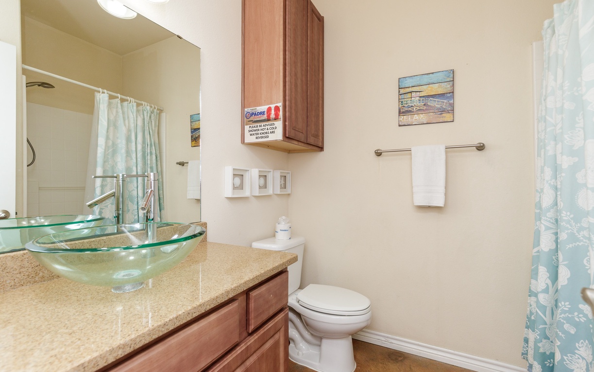 Your bright bathroom features a glass bowl sink, granite counters, and coastal decor for a refreshing start to your day.