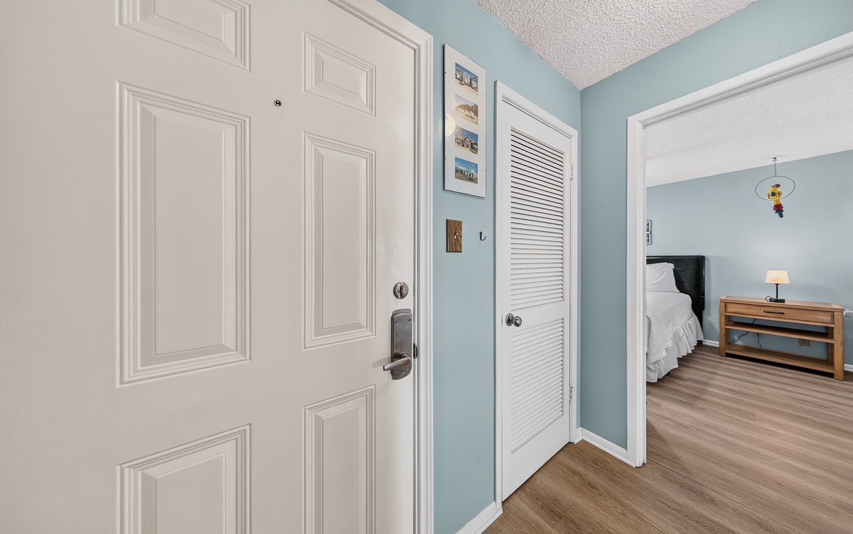 Step inside your peaceful retreat, where calm blue walls and warm wood floors greet you. A cozy bedroom waits just beyond—your home away from home begins right here.