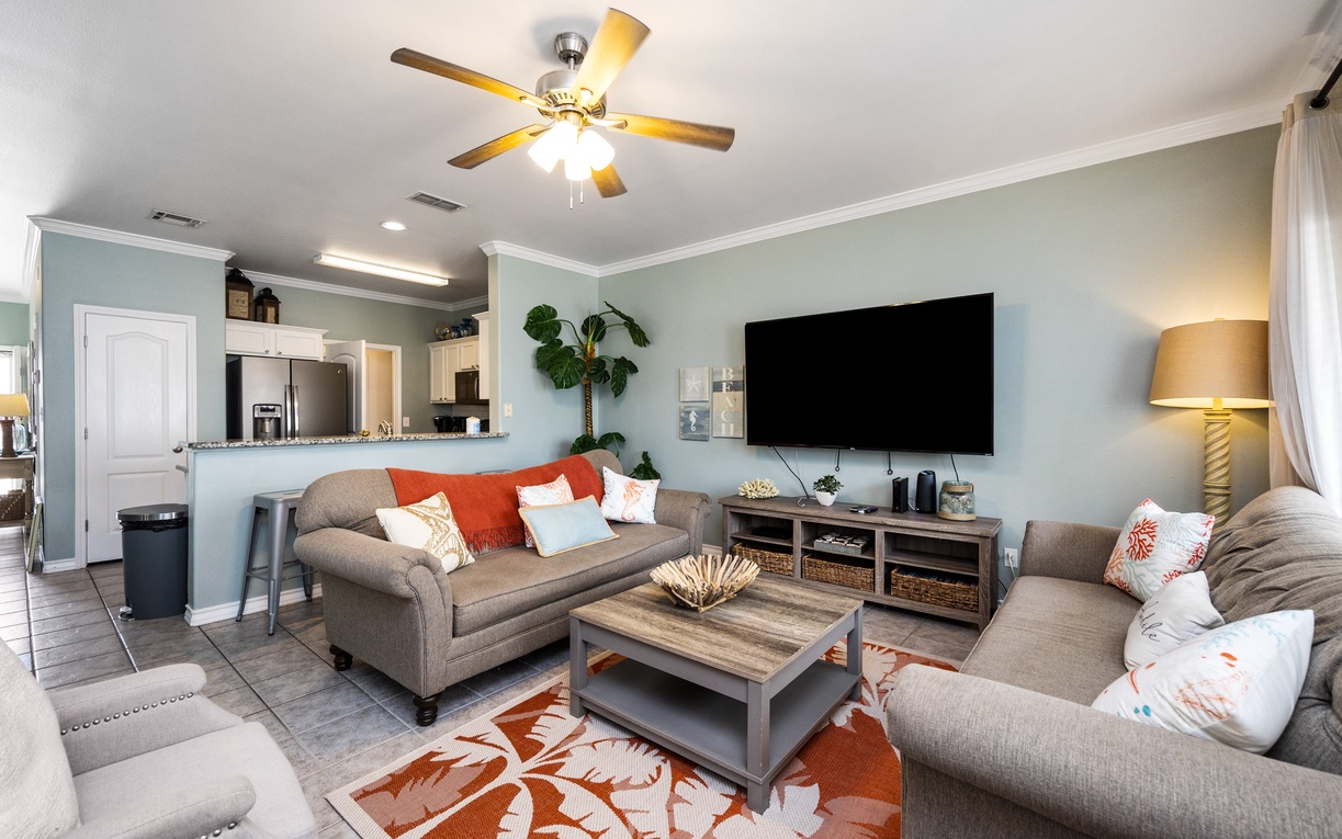 Relax in your stylish living room with comfortable seating, large TV, and open kitchen—perfect for unwinding after your adventures.