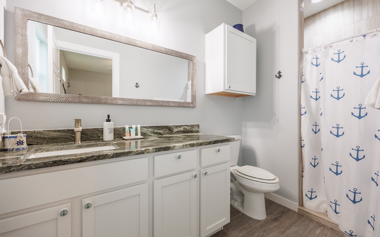 Step into your nautical-themed bathroom featuring granite countertops, crisp white cabinetry, and charming anchor accents throughout.