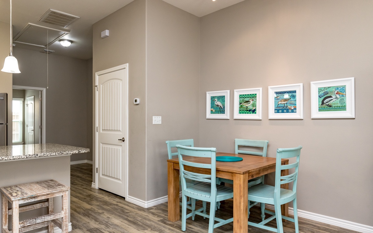 Your cozy dining nook features a warm wood table with cheerful turquoise chairs, perfect for morning coffee or intimate meals together.