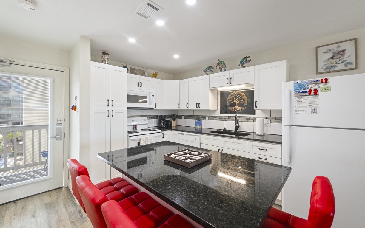Your fully equipped kitchen features sleek granite countertops, white cabinetry, and modern appliances, perfect for preparing meals together during your stay.